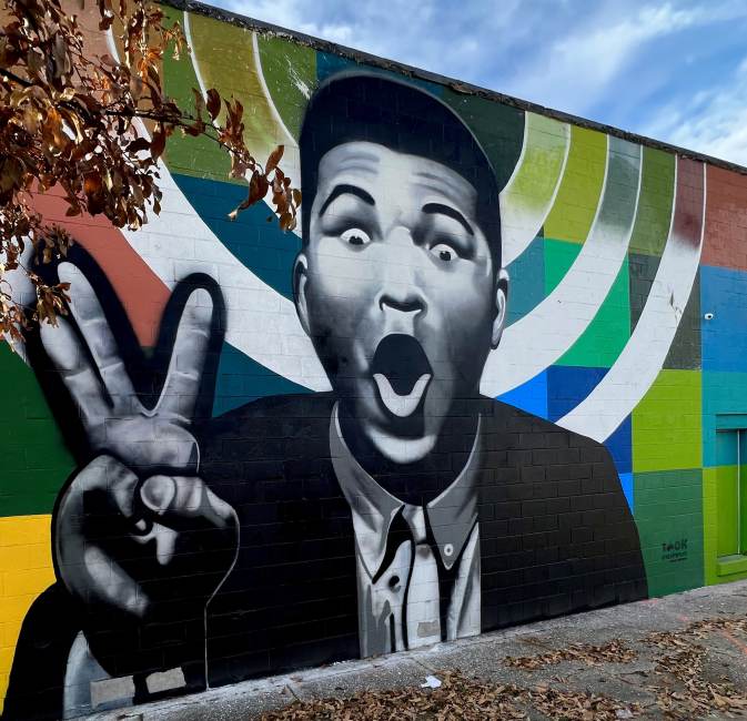 Louisville Digitizes Urban Art Catalog black and white mural of Muhammad Ali with a colorful background on a building in Louisville