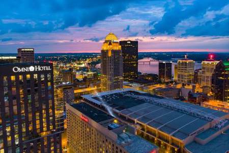 Louisville skyline shot from the South with a view of tall buildings, river at twilight.